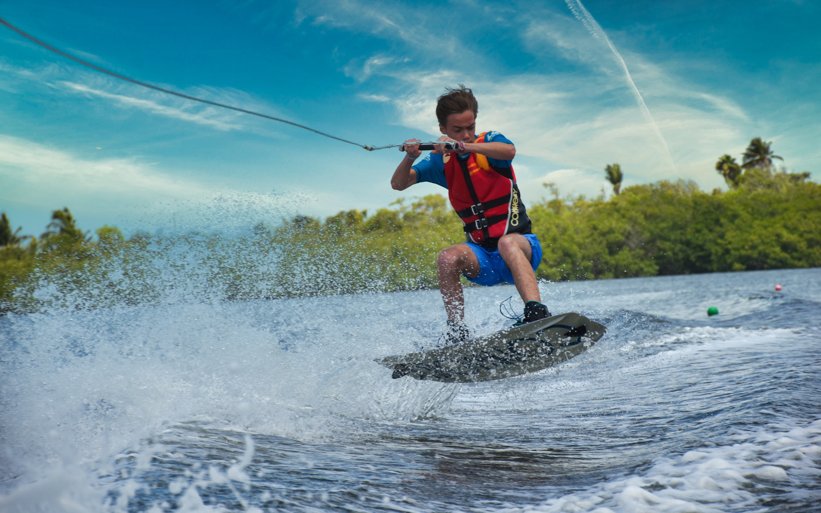 person in life jacket on water wakeboarding